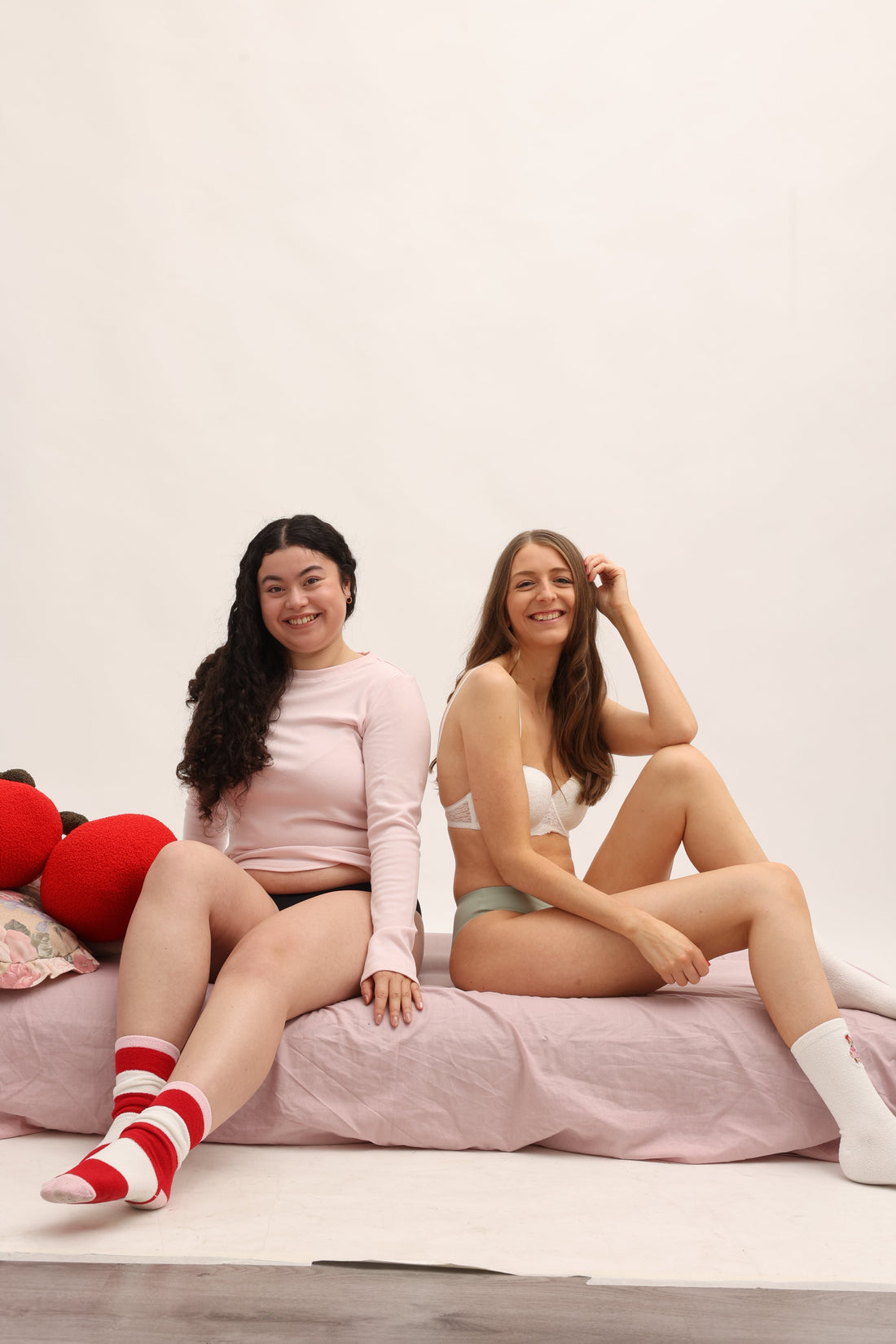 Two women relaxing on bed wearing comfortable reusable menstrual underwear for everyday protection